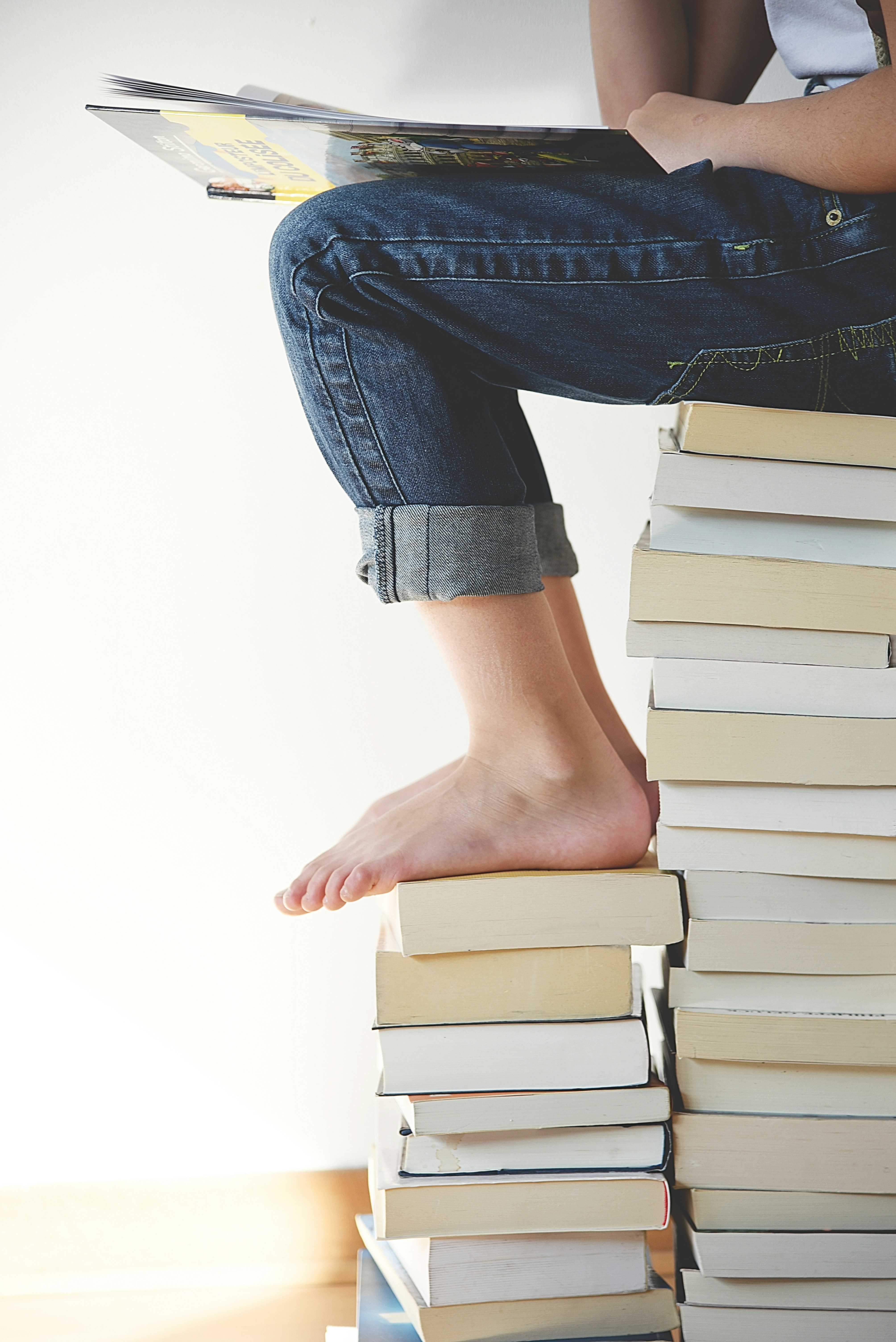 Kids leg as they are sitting on a stack of books.